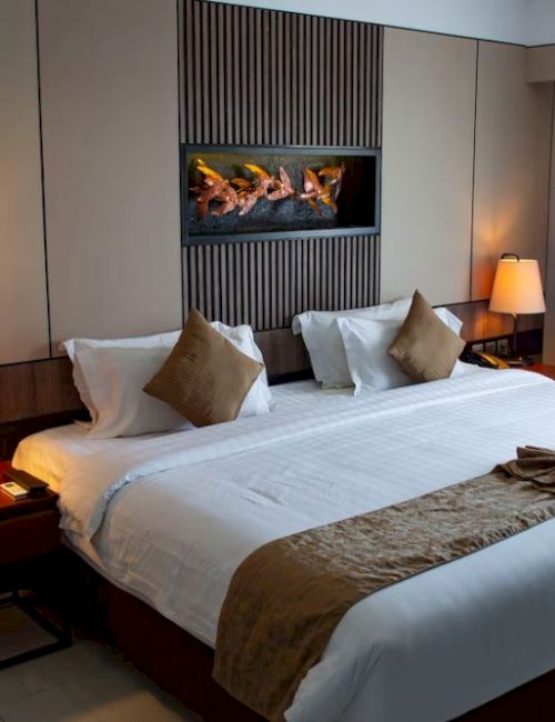 A well-decorated hotel room with a large bed, bedside tables with lamps, and a modern artwork above the bed's headboard.