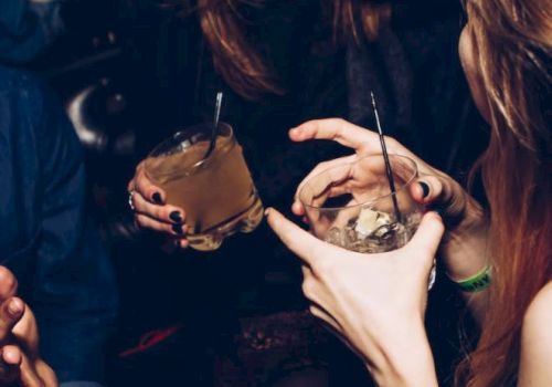 People are socializing, holding drinks, and smiling, likely at a party or gathering.