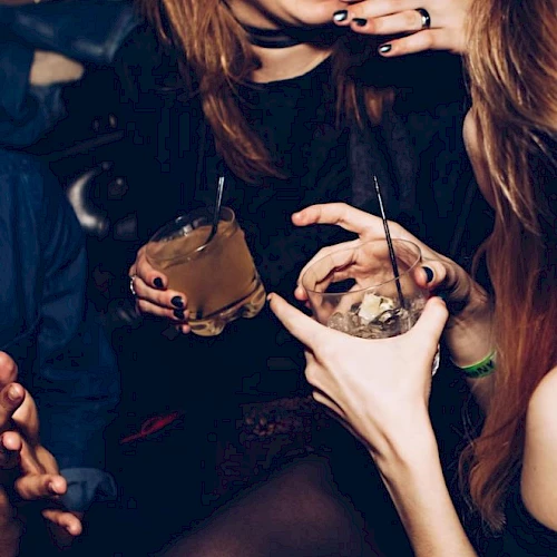 People are socializing, holding drinks, and smiling, likely at a party or gathering.