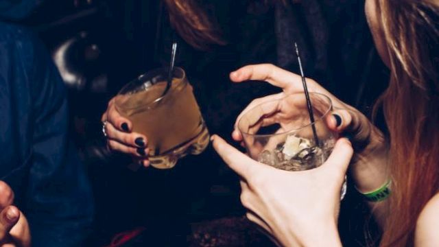 People are socializing, holding drinks, and smiling, likely at a party or gathering.